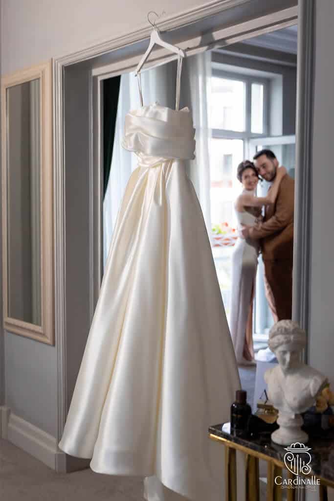 fotograf surprinzand cuplul de miri privind la rochia de miresa in timpul unei nunti